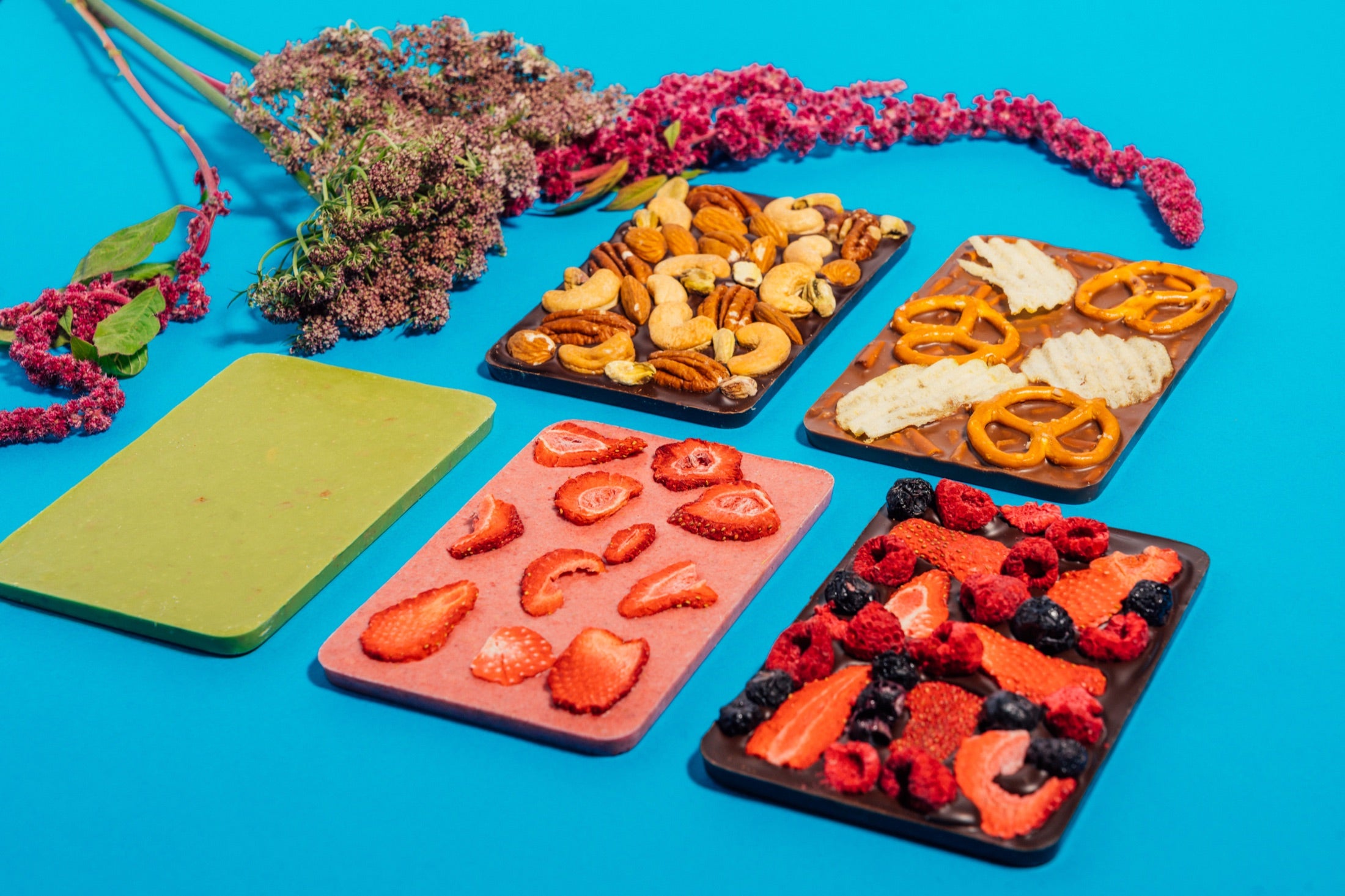 Colorful Socola chocolate bars topped with fruit, nuts, and pretzels on a bright blue background