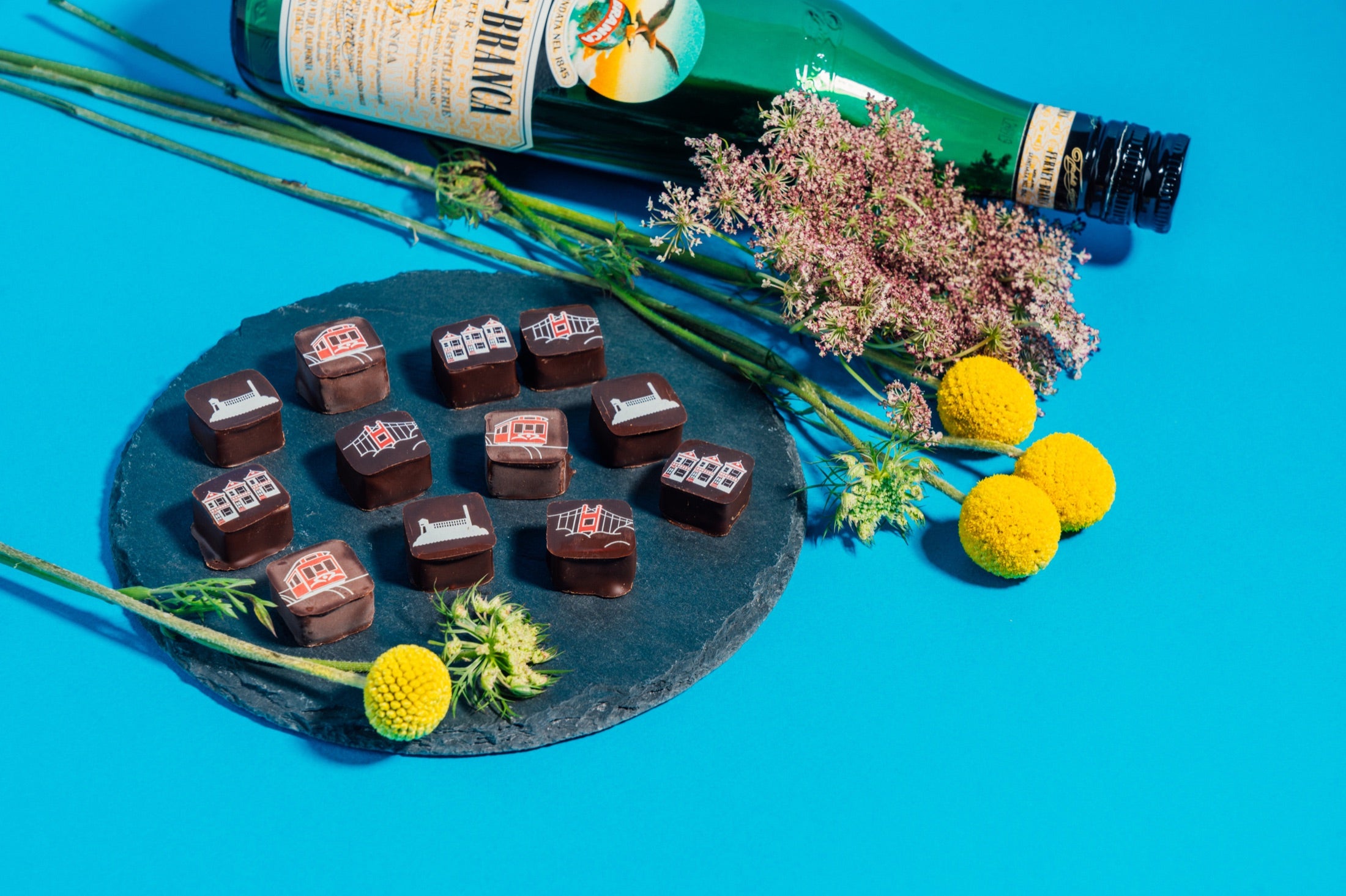 Custom San Francisco chocolates styled with flowers on a bright blue background