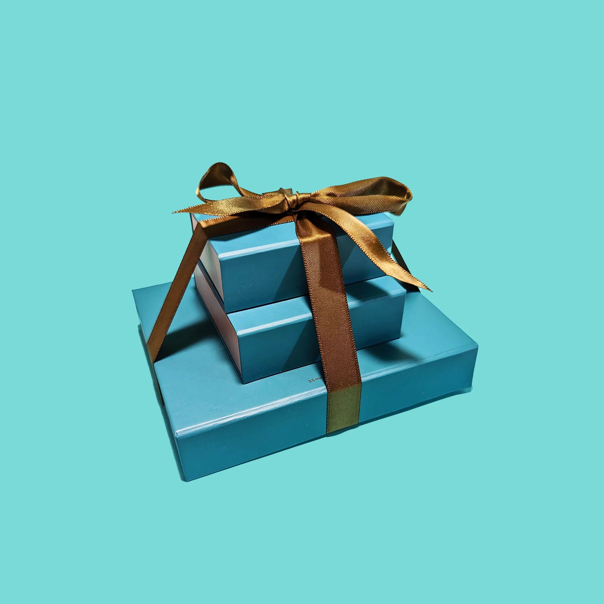 Three teal Socola chocolate boxes stacked as a gift tower with ribbon